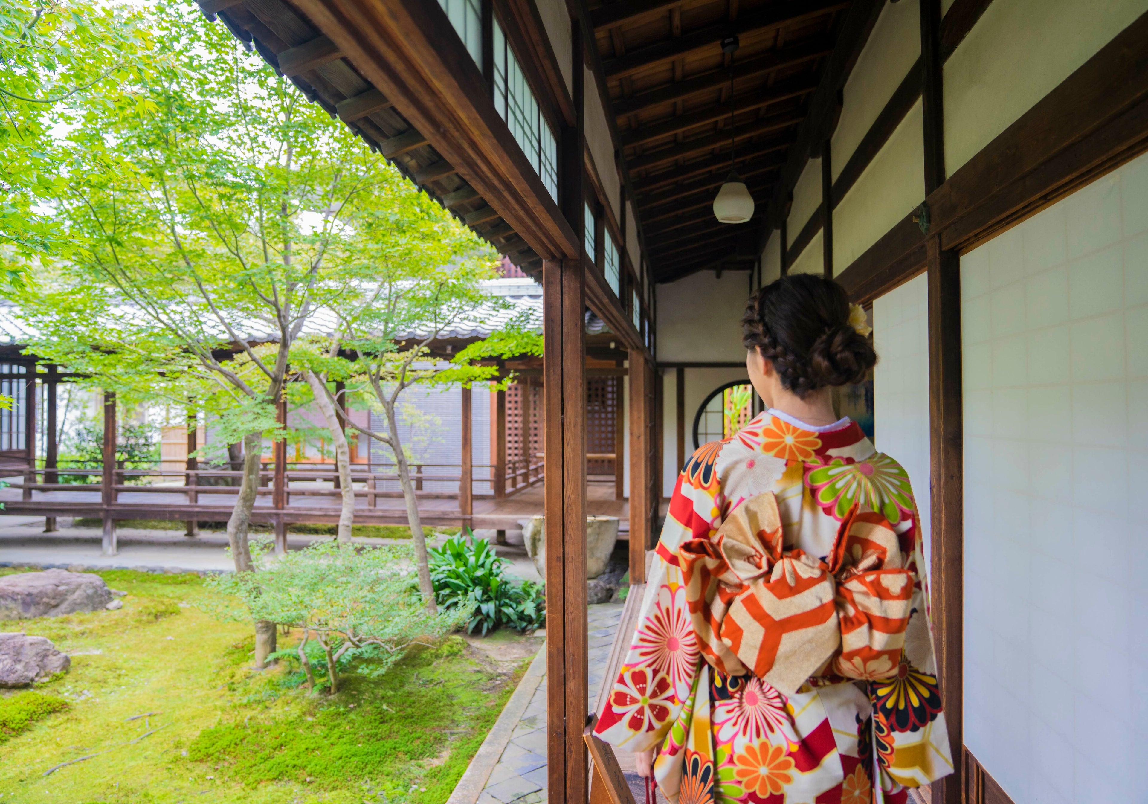 着物を着た女性が日本庭園を散歩している画像。色鮮やかな着物を身にまとい、風情ある日本庭園の小道を歩いています。古くから受け継がれてきた日本の伝統美が感じられる一枚です。